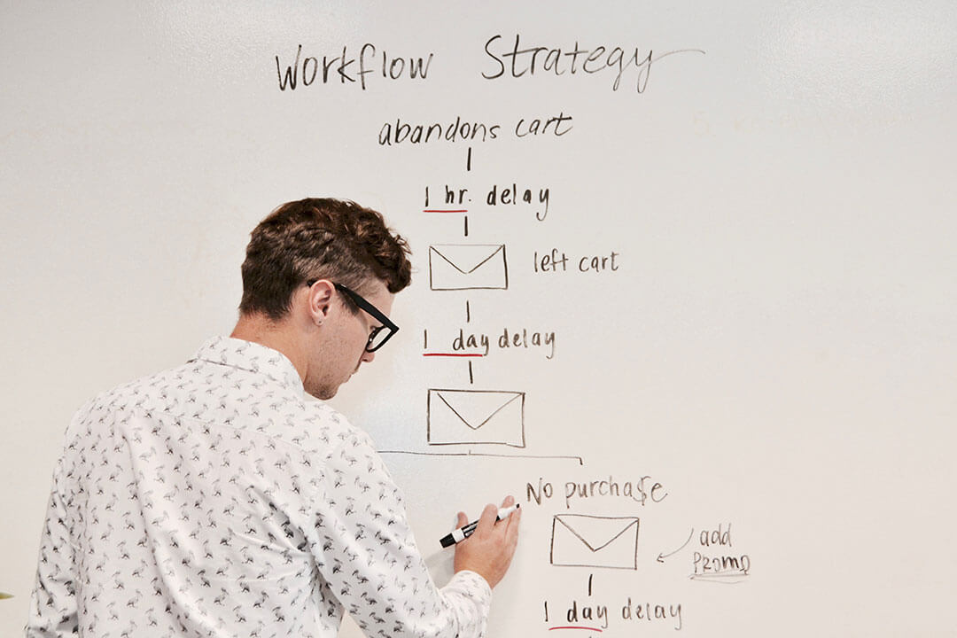 Person writing schematic online campaign strategy on whiteboard