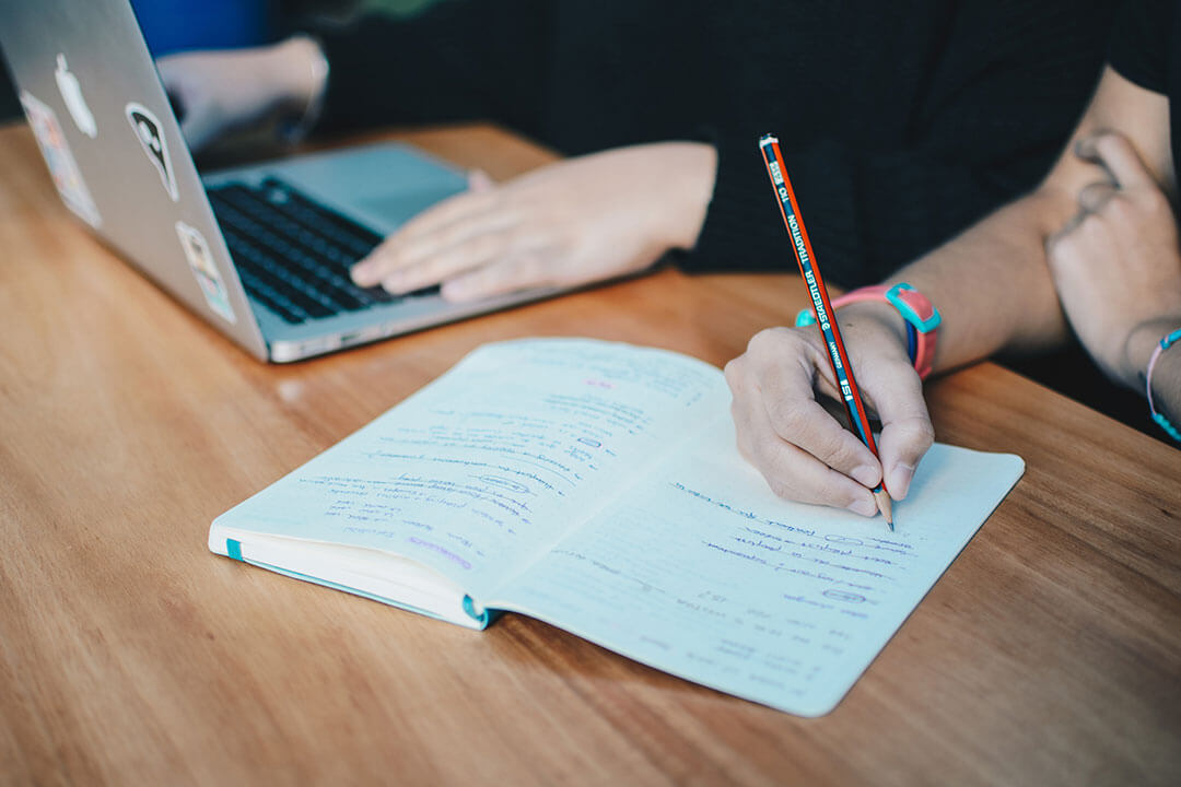 Two people with notebook and laptop working on strategy together